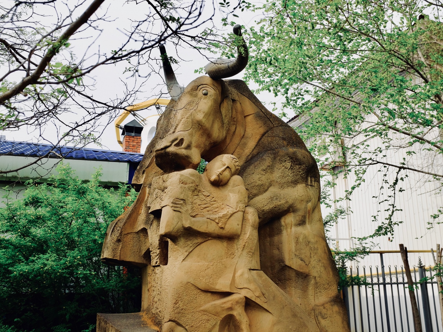 Sculpture on the sidewalk of Elista, Russia, depicting a man and a large horned mammal, possibly a Kalmyk cattle.